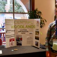 Central Woodlands' student poses by the school's table and poster about climate change